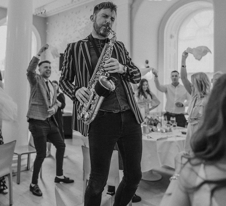 Wedding entertainment saxophonist playing his saxophone wearing striped blazer 