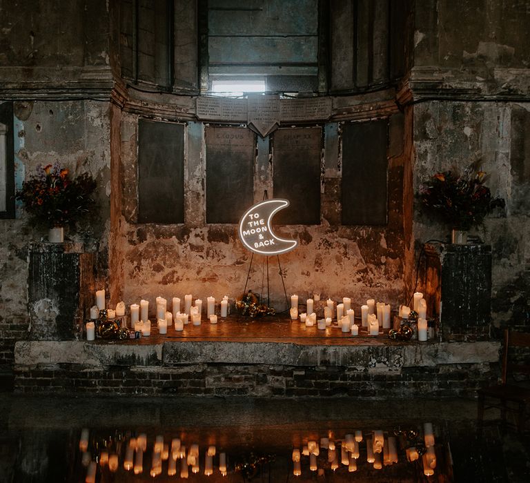 Stunning wedding alter consisting of candles and a moon neon sign at unique wedding venue in London