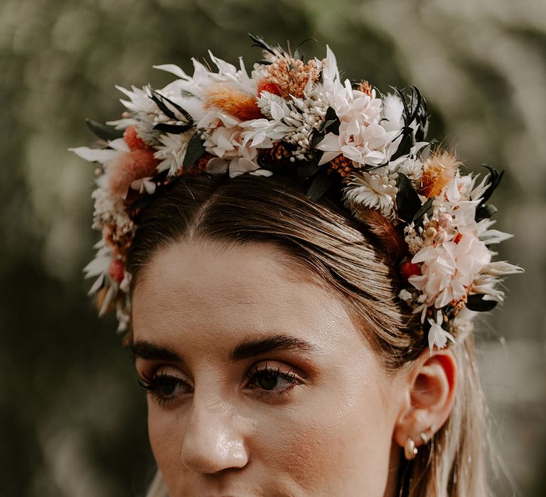 Bride with short blonde hair and gold earring stack with smoky brown makeup wearing a dried flower headband 