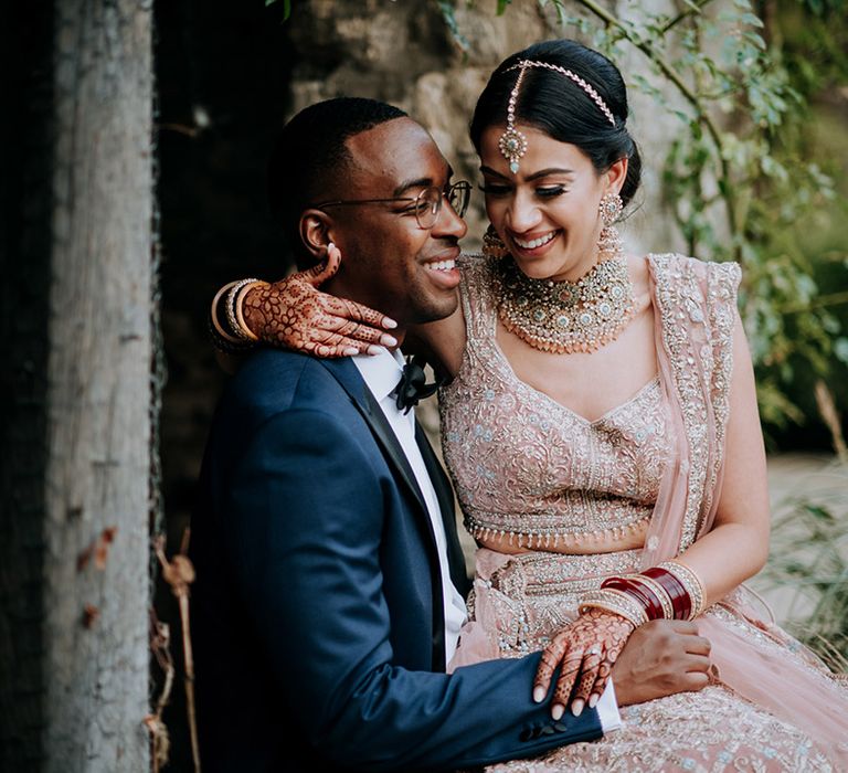 Bride sits on Groom's lap in the grounds of Caswell House