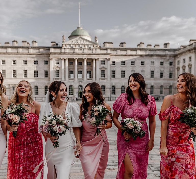 Bride with bridesmaids in mismatched bridesmaid dresses in different styles and patterns for contemporary city wedding 