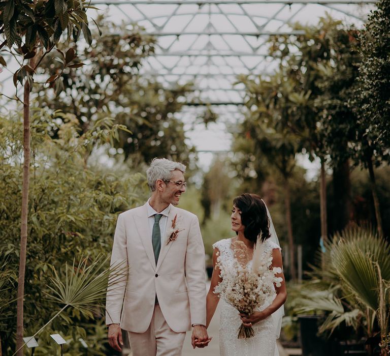 Glasshouse wedding with the groom in a cream suit and green tie with the bride in a pretty mermaid wedding dress