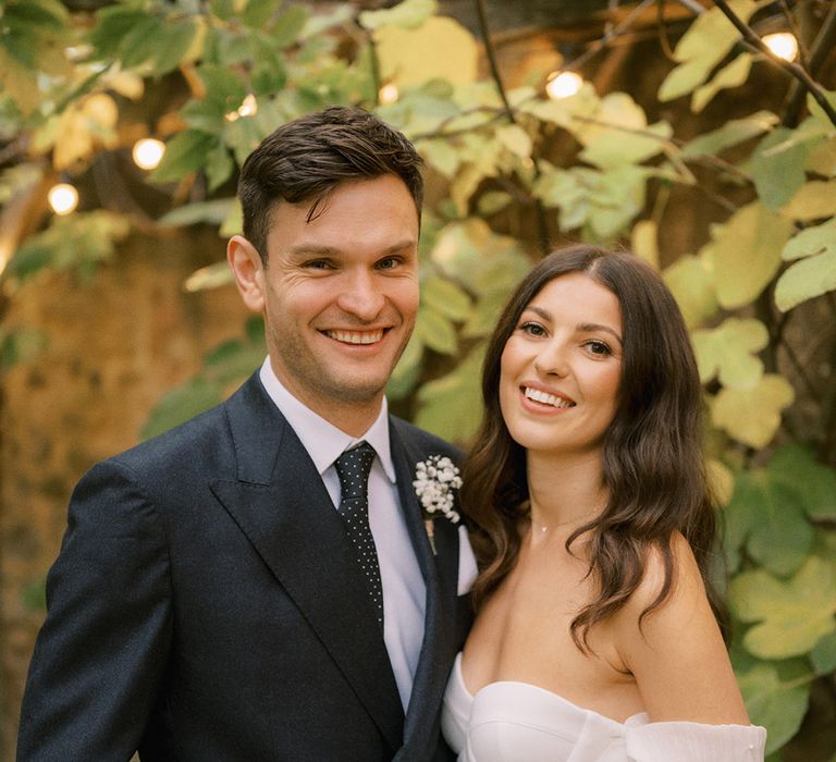 Groom in dark suit with spotted tie with bride in Bon Bride corset style wedding dress for rustic luxe wedding at The Tythe Barn