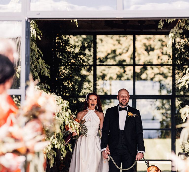 The bride and groom exit their ceremony with their pet dog 