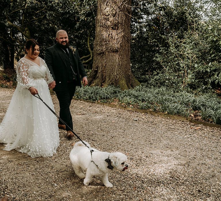 The bride and groom walking around with their pet dog 