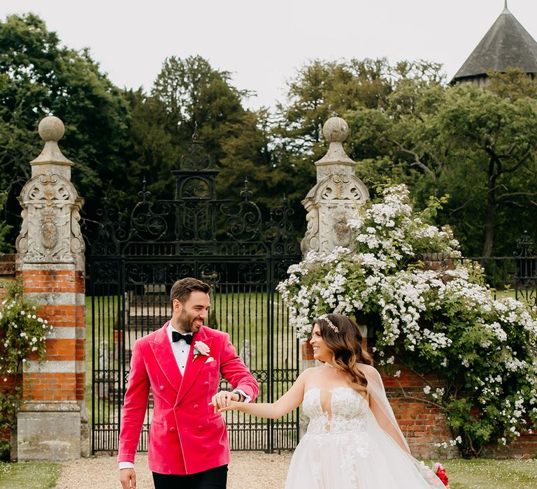 Groom in vibrant pink velvet groom suit with the bride for luxury wedding 