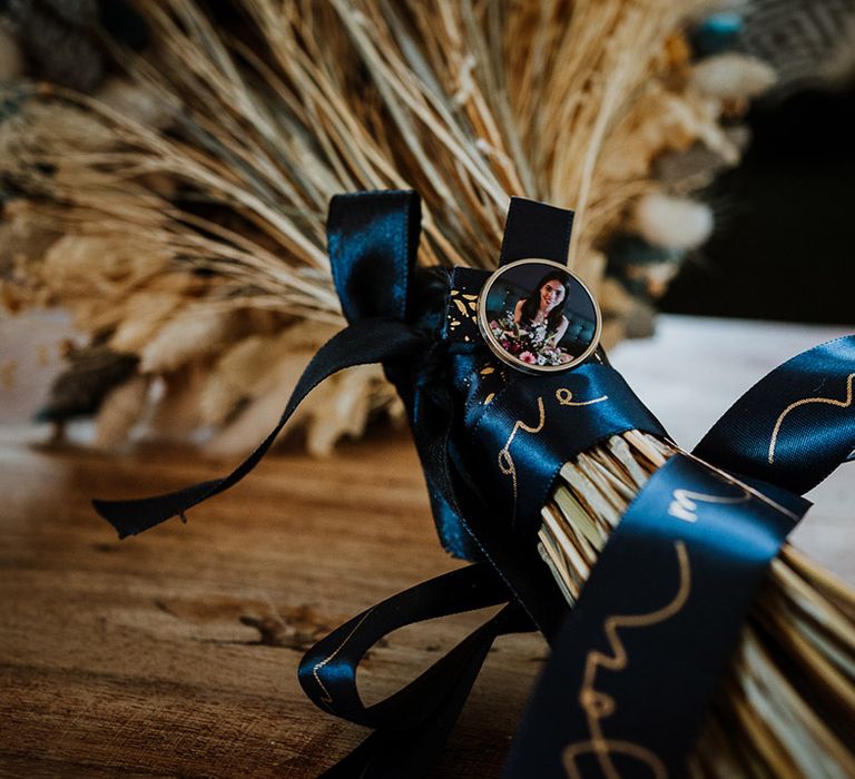 Dried wedding flower bouquet with dark blue ribbon and personalised pin of the maid of honour 