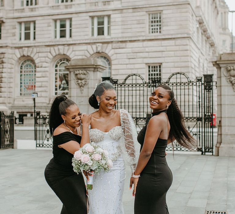 Bride in sequin sparkly wedding dress at city wedding with two bridesmaids in black fitted dresses