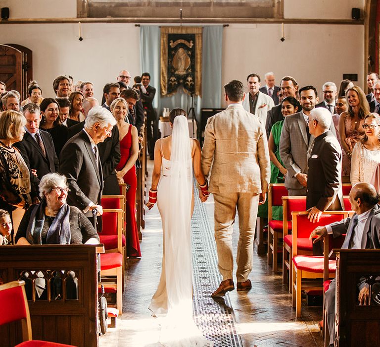 The bride and groom walk back down the aisle together as a married couple