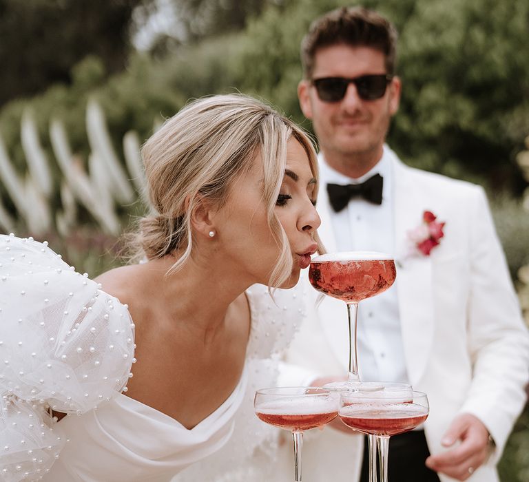 Bride sipping from pink champagne tower wedding decor 