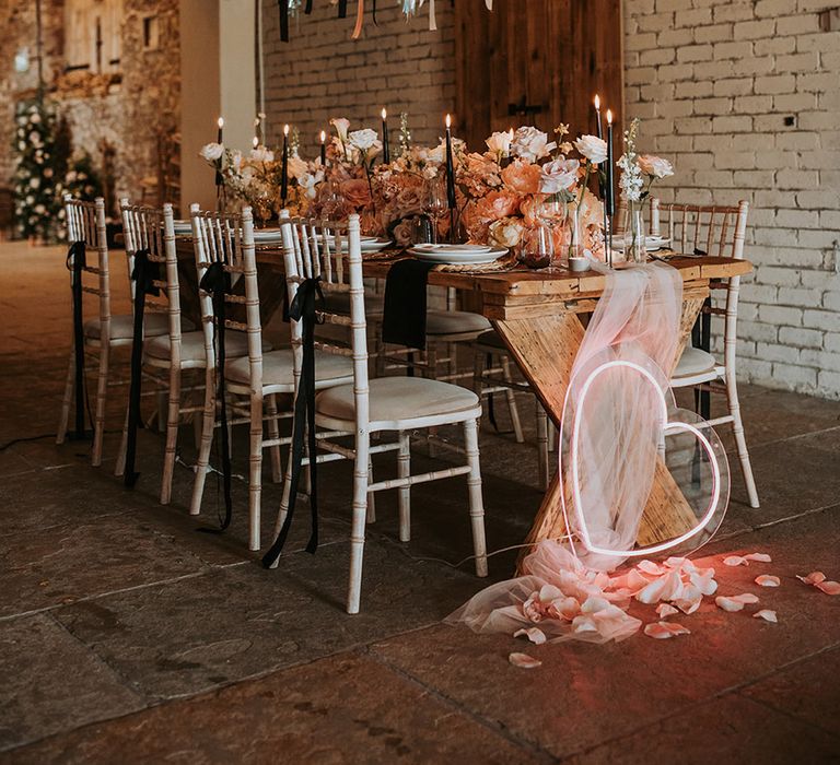 Eden Barn rustic wedding with stunning pink and black wedding tablescpae including pink heart neon sign, fringed garland or streamer decorations and blush florals 