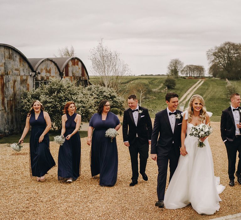 Wedding party posing for group photo outside wearing black tie and navy bridesmaid dresses at Stone Barns wedding venue 