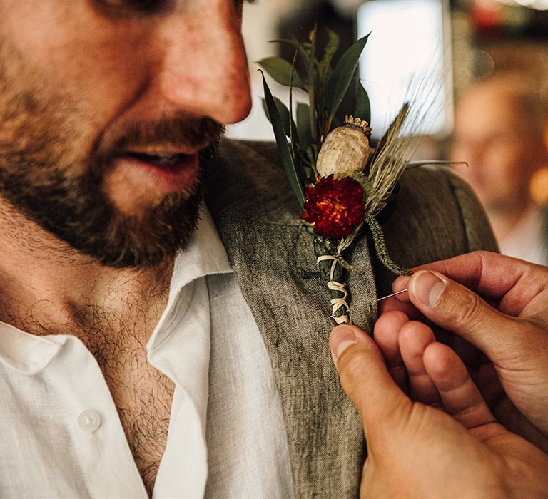 Groom in grey suit wearing a floral buttonhole for church wedding and tipi wedding reception 