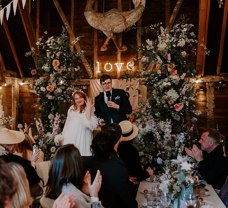 Joint wedding speech performed by the bride and groom in front of their sweetheart table 