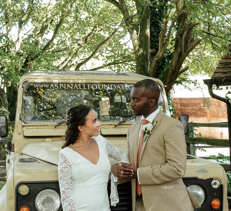 Safari Jeep wedding car with bride in a long sleeve boho wedding dress with groom in a beige suit 