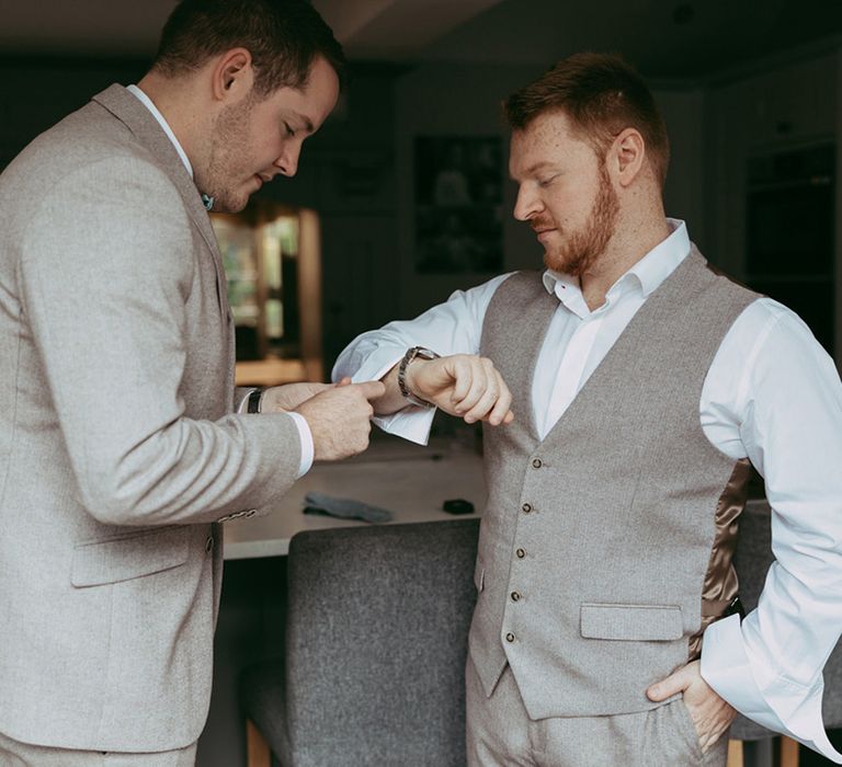 Groomsman helps the groom get ready for the wedding day 