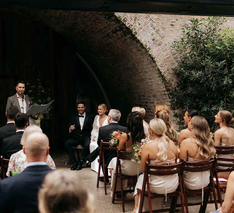 The bride and groom at their wedding ceremony with the guests seated watching on 