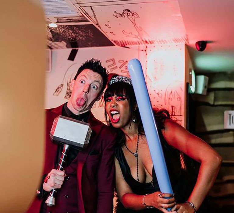 Guests posing with fun props in a wedding photo booth 