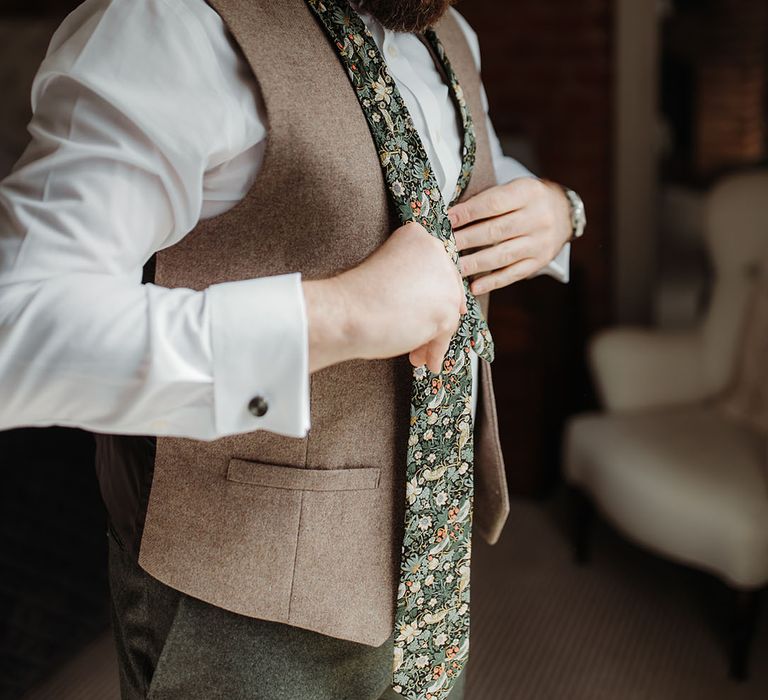 Groom wearing floral patterned tie with light brown waistcoat getting ready for the wedding 