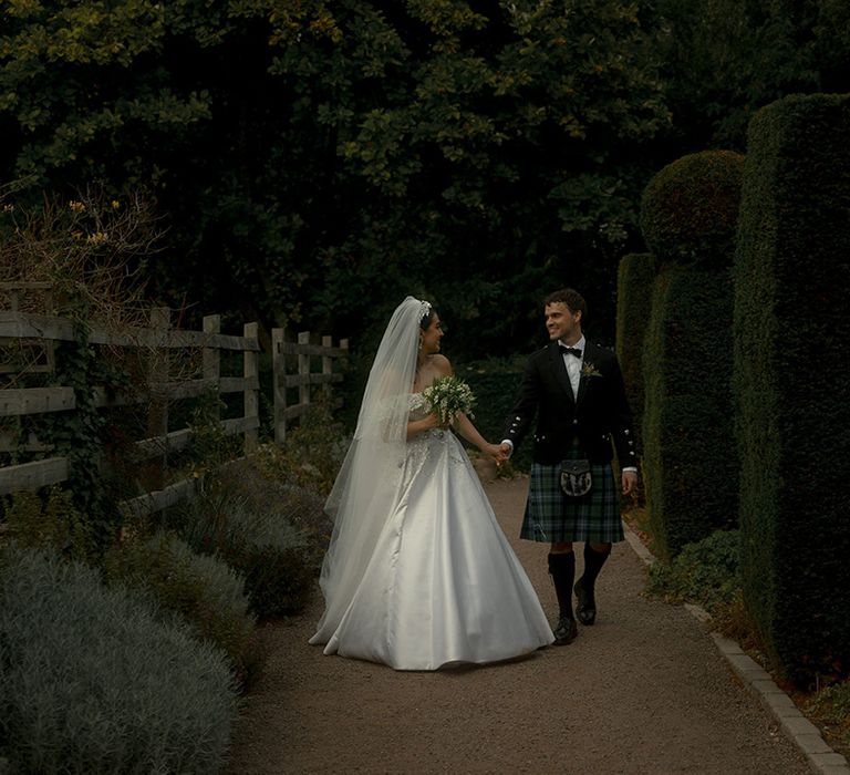 Bride in bespoke princess wedding dress and veil with the groom in a black tuxedo with tartan kilt for Scottish-Iranian wedding 