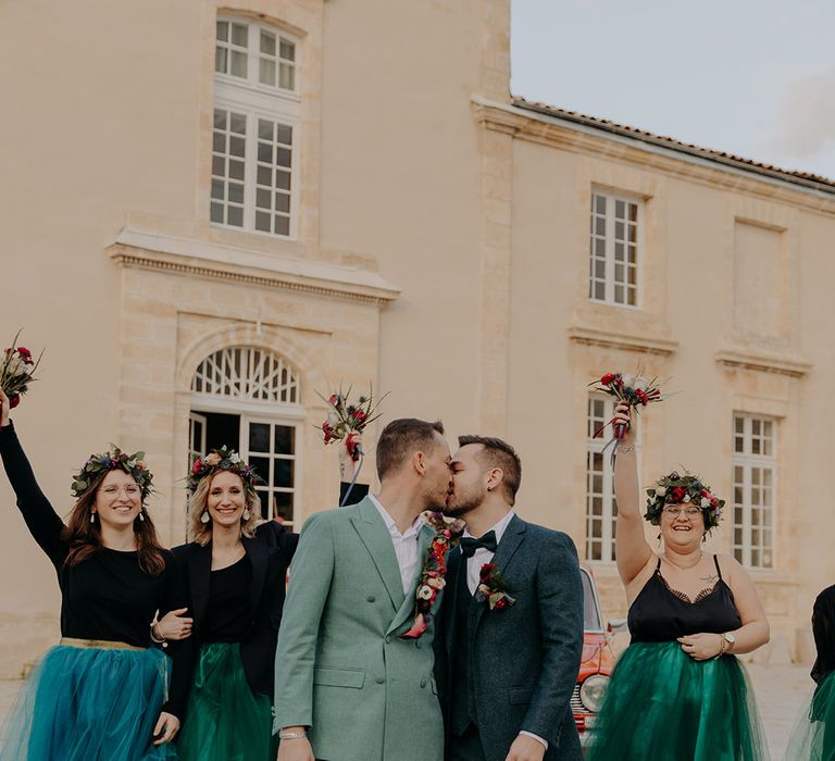 Bridesmaids in tulle tutu bridesmaid dresses with the two grooms who share a kiss as their wedding 