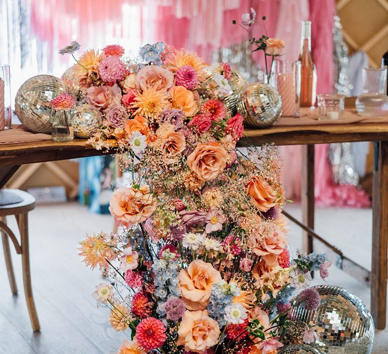 Colourful wedding flower arrangements on the top table with disco balls 