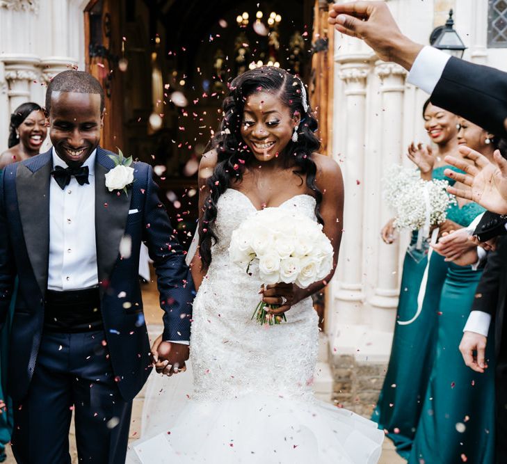 Bride and groom confetti moment with all white wedding bouquet 