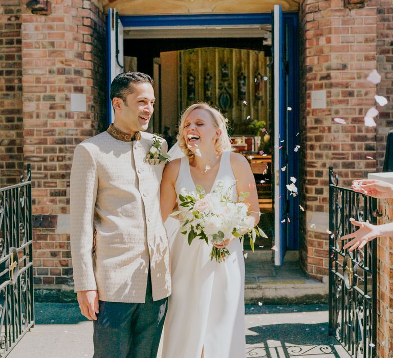 Confetti moment with bride in White by Vera Wang wedding dress and groom in gold suit jacket