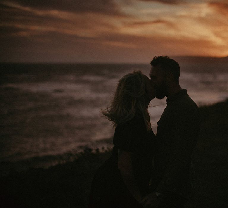 Golden hour portrait on the beach with couple kissing 