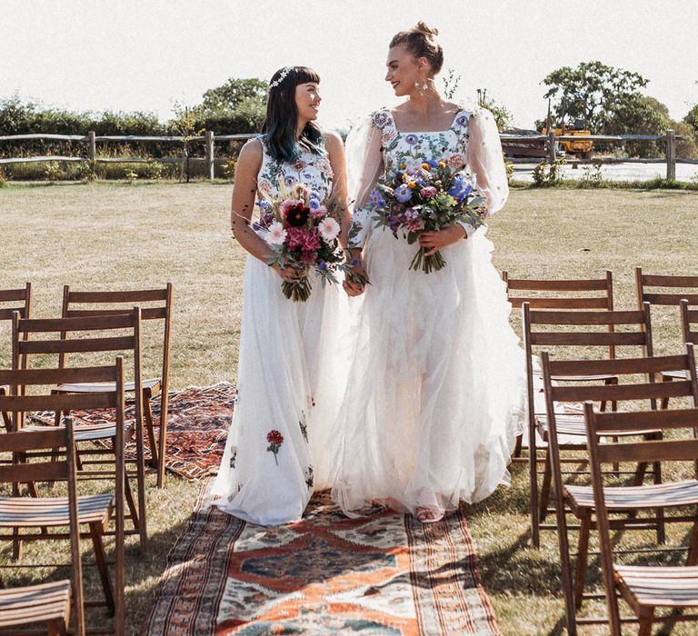 Same sex couple walking down the aisle in flower embroidered wedding dresses 