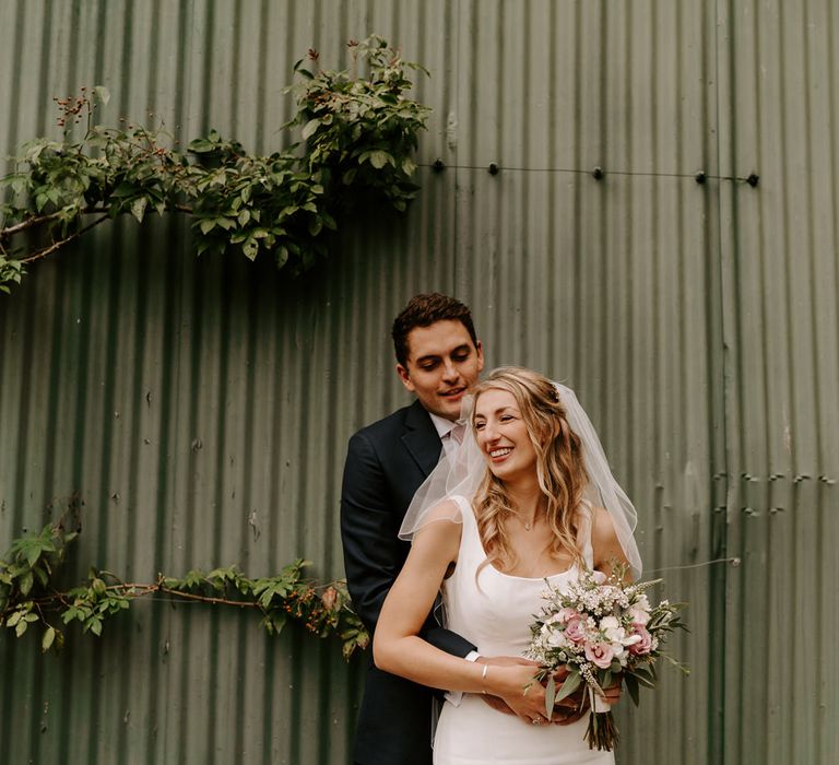 Groom embracing his bride in an elegant wedding dress with straps 