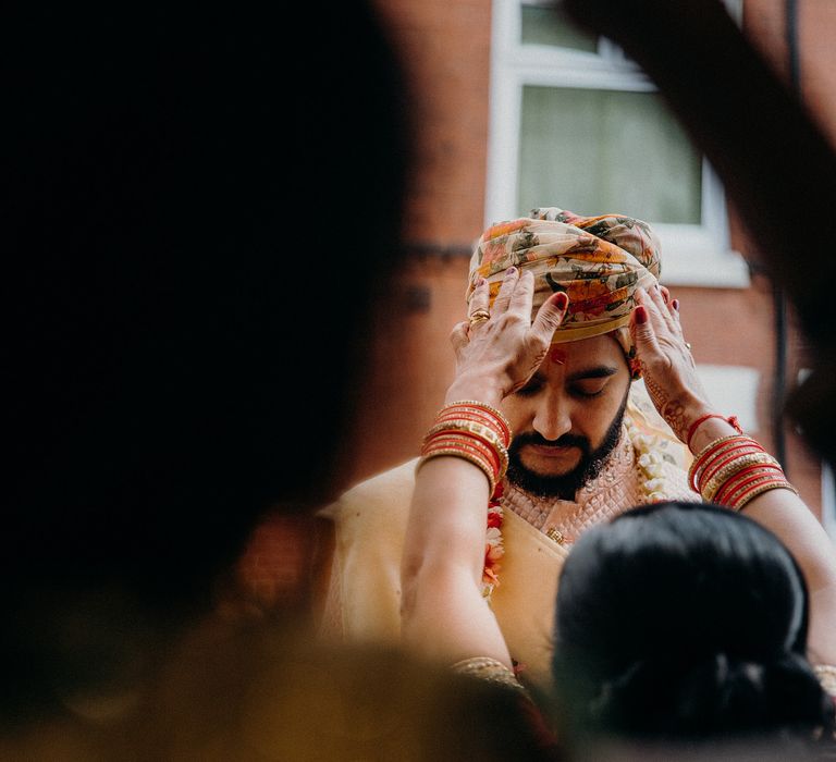 Groom has turban adjusted by wedding guest