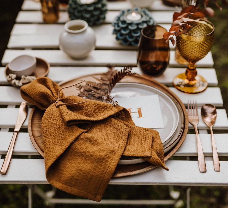 Boho table setting with brass knives and forks and wooden placemats