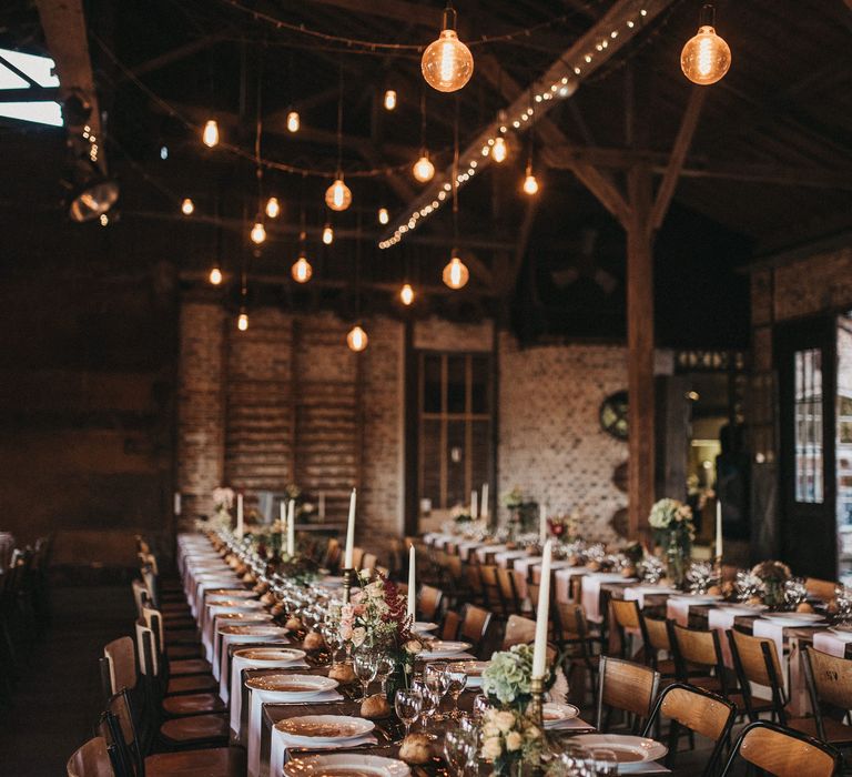 Banquet wedding tables with wooden chairs different tableware, taper candles and flower centrepieces 