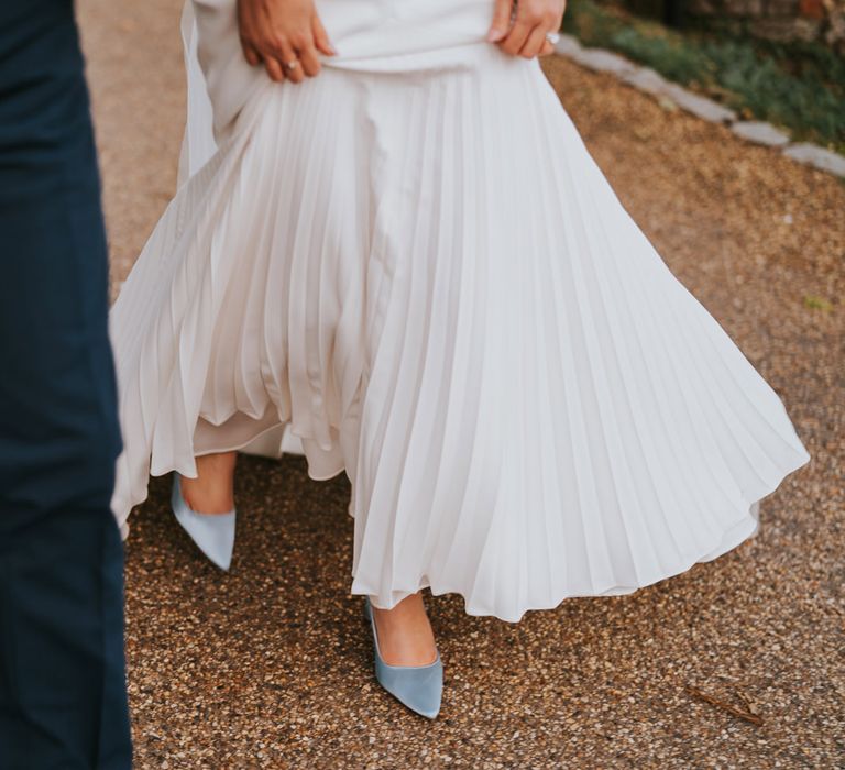 Bride & groom walk together outdoors with bride wearing Rainbow Club shoes