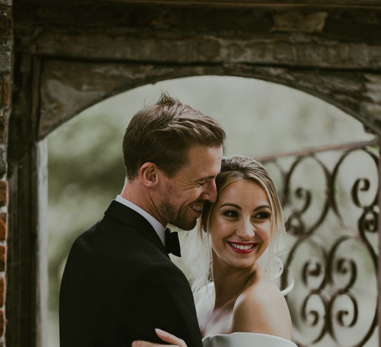 Groom leans into brides hair outdoors