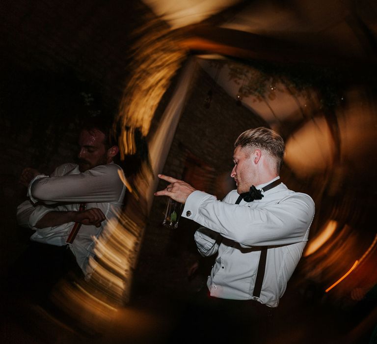 Groom in white shirt, black braces and black velvet bow tie dances at Caswell House wedding