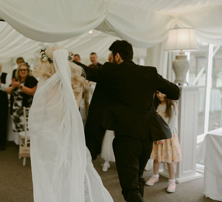 Bride in Grace Loves Lace wedding dress and single tier cathedral length veil walks into marquee groom in black Hugo Boss suit at Drenagh Estate Wedding