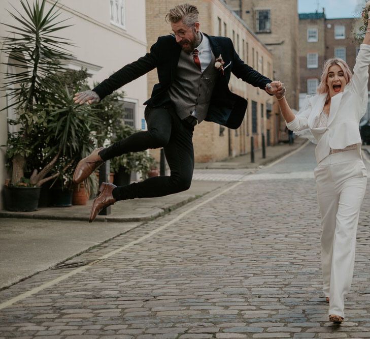 Groom jumps in the air and bride throws up hands in celebration