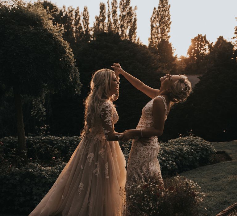 Two brides dance outside at sunset.