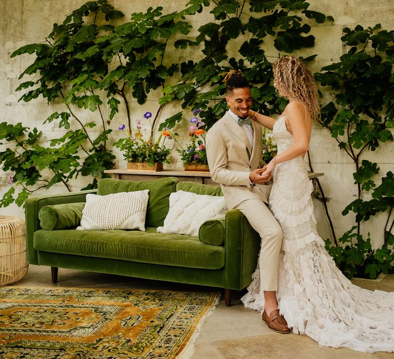 Groom in a beige suit and green bow tie and bride in a boho lace dress at their colourful fiesta theme wedding 