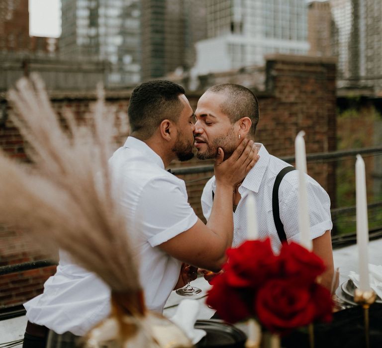 Grooms share a kiss at intimate rooftop elopement