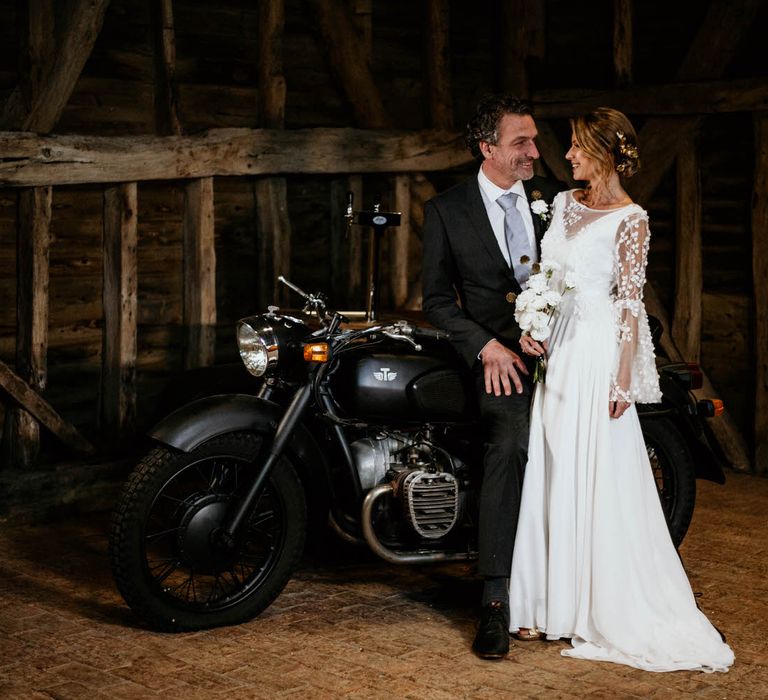 Bride and groom learning against a cocktail bar shaped like a motorbike