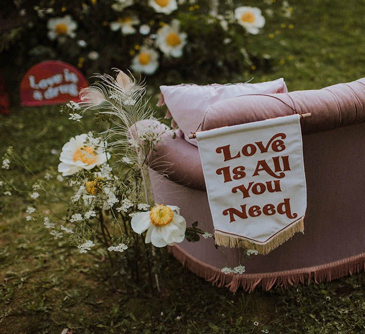 Love Is All You Need fabric banner wedding sign resting on the back of a retro sofa 