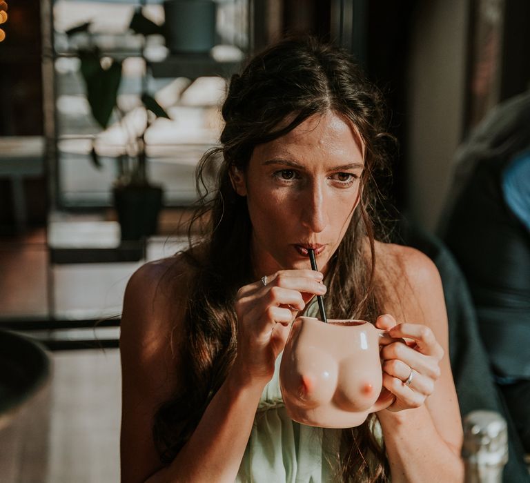 Bridesmaid sips from breast cup at wedding reception