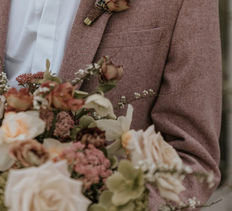 Groom in a chalky pink blazer with baby hyacinth buttonhole flower 