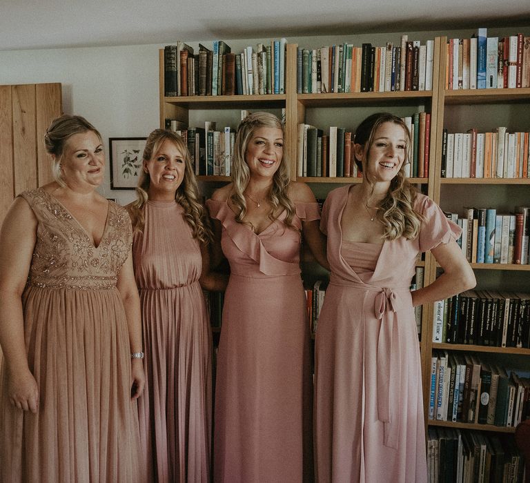 Bridesmaids wear pale pink bridesmaids gown in differing styles