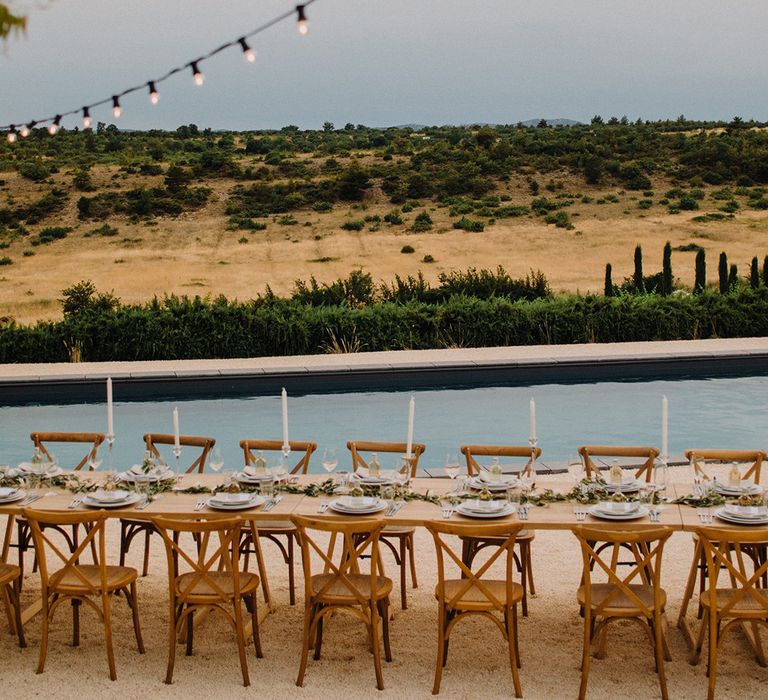 Rustic table setting looks across fields in Croatia complete with hanging fairy lights