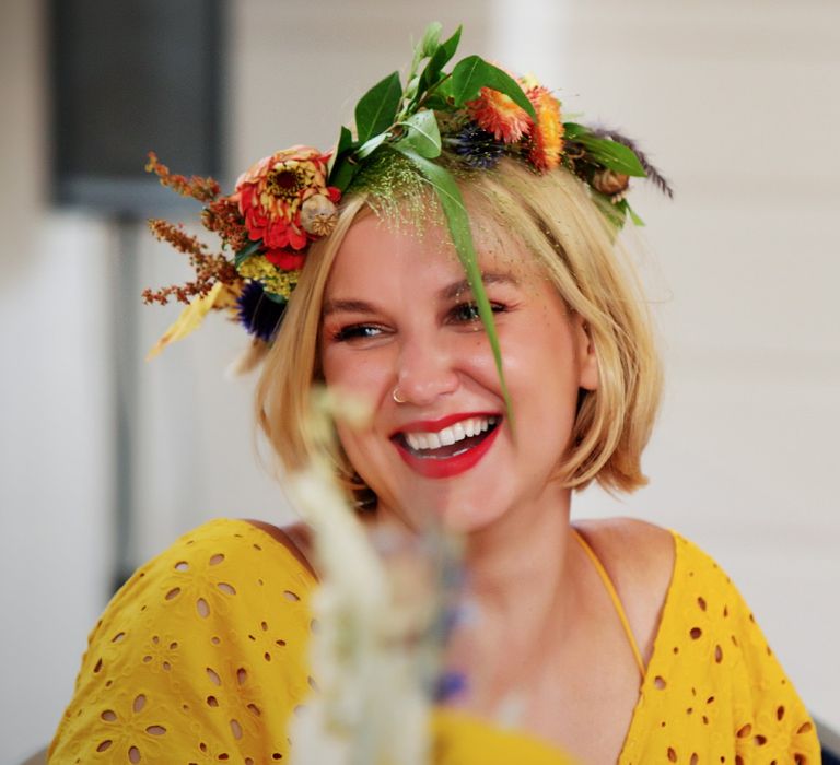 Groomsmaid wears yellow wedding gown complete with flower crown and red lipstick