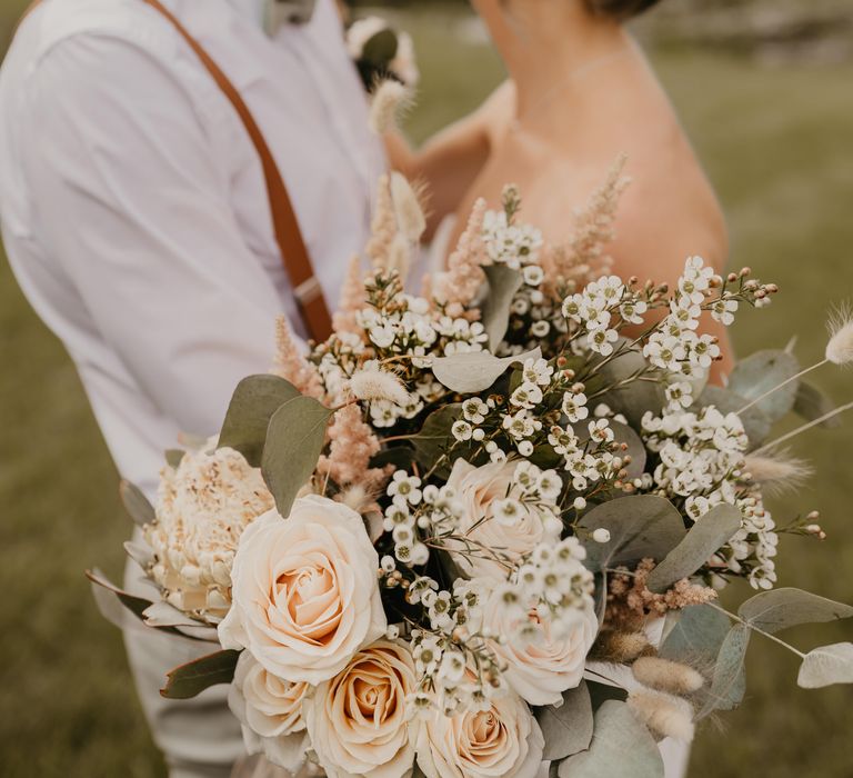 Bride & groom kiss on their wedding day as bride holds out her floral bouquet | Mark Bamforth Photography